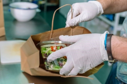 A healthy salad is packed into a paper bag in a kitchen